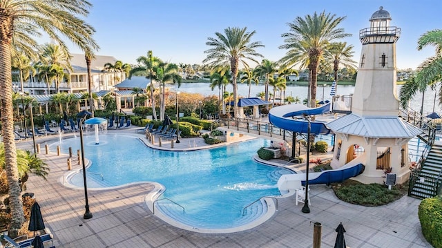 pool featuring a patio area, a water slide, and a water view