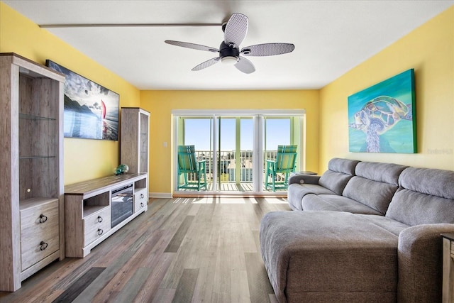 living room with baseboards, ceiling fan, and wood finished floors