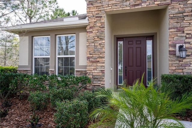 entrance to property featuring stone siding and roof with shingles