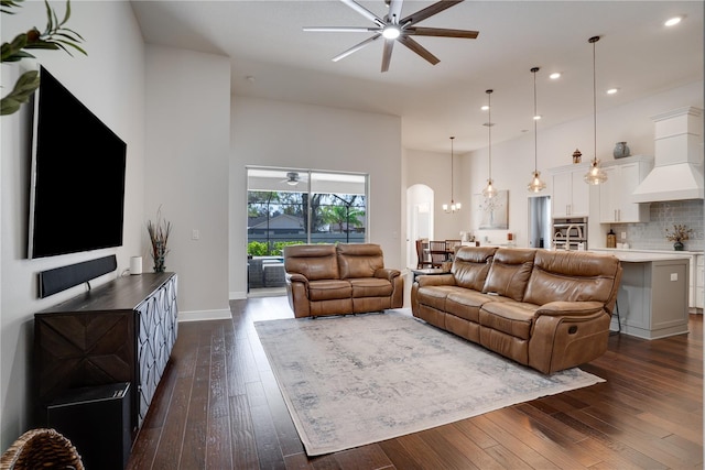 living area featuring arched walkways, dark wood finished floors, and ceiling fan