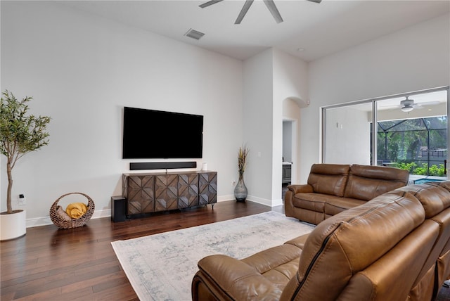 living room with baseboards, visible vents, arched walkways, ceiling fan, and dark wood-type flooring