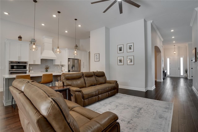 living area with baseboards, arched walkways, dark wood finished floors, ornamental molding, and recessed lighting