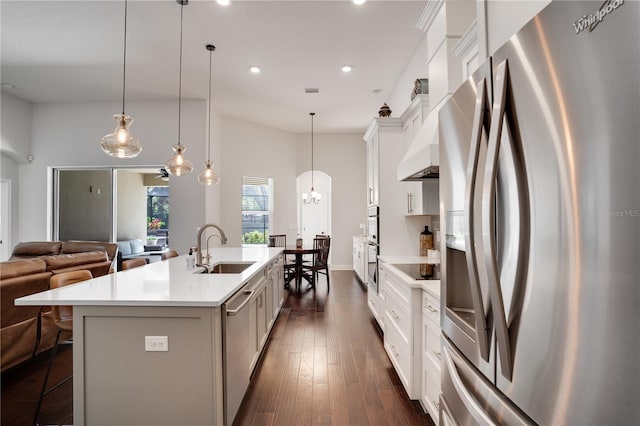 kitchen with a center island with sink, open floor plan, stainless steel appliances, light countertops, and a sink