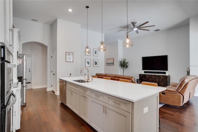 kitchen with arched walkways, a sink, visible vents, open floor plan, and dark wood finished floors