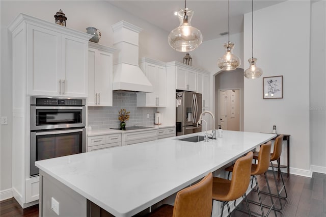 kitchen featuring stainless steel appliances, a spacious island, backsplash, a sink, and premium range hood