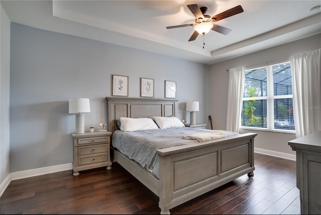 bedroom featuring dark wood-style floors, ceiling fan, baseboards, and a raised ceiling