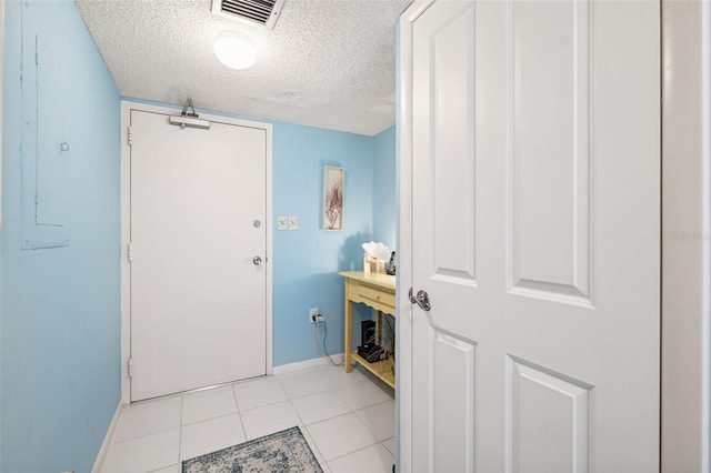 interior space featuring light tile patterned floors, baseboards, visible vents, electric panel, and a textured ceiling