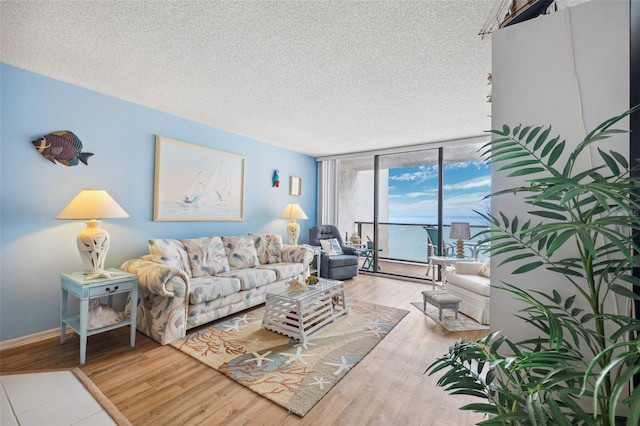 living room featuring expansive windows, baseboards, a textured ceiling, and wood finished floors