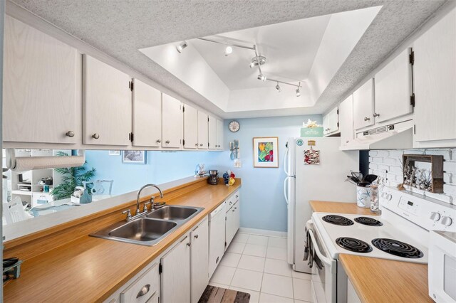 kitchen with white range with electric cooktop, a tray ceiling, light tile patterned flooring, a sink, and under cabinet range hood