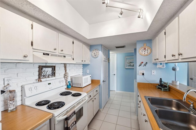 kitchen with white appliances, light tile patterned flooring, a sink, under cabinet range hood, and backsplash