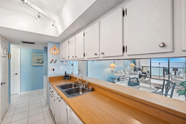 kitchen with a sink, white cabinetry, light tile patterned flooring, light countertops, and baseboards