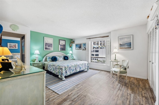 bedroom with a closet, baseboards, a textured ceiling, and wood finished floors