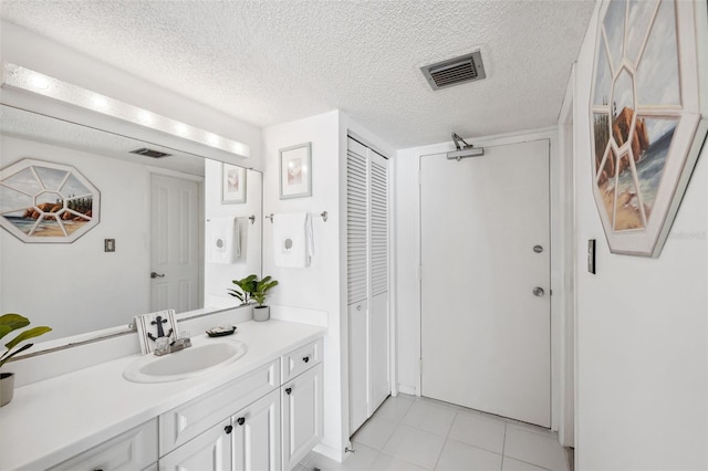 bathroom with tile patterned floors, visible vents, a textured ceiling, and vanity