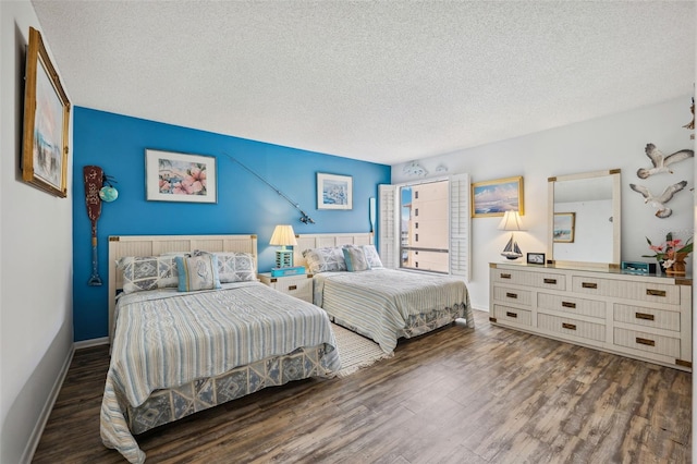 bedroom featuring a textured ceiling, baseboards, and wood finished floors