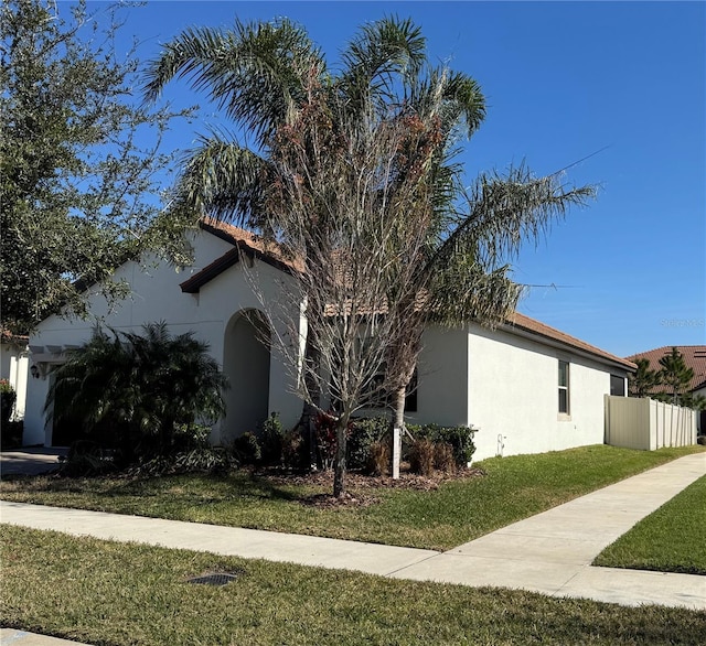 view of home's exterior featuring stucco siding, a yard, an attached garage, and fence