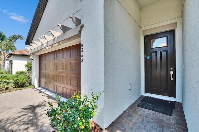 property entrance with an attached garage and stucco siding
