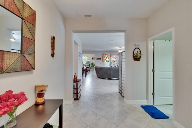 corridor featuring light tile patterned floors, visible vents, and baseboards