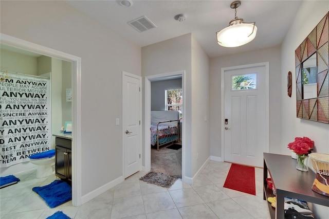foyer featuring light tile patterned flooring, visible vents, and baseboards
