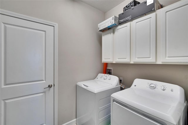 laundry room with cabinet space, a textured ceiling, and washing machine and dryer
