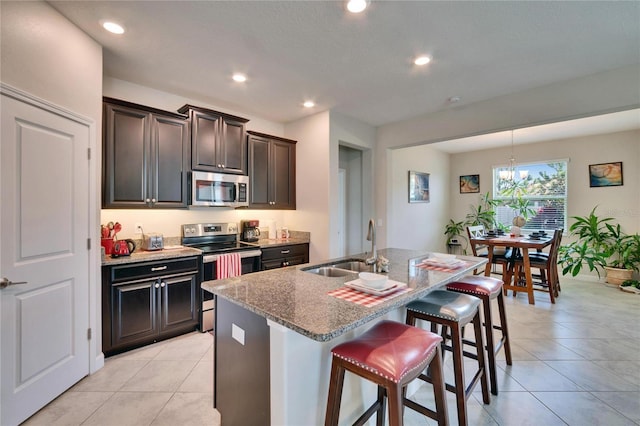 kitchen with a sink, stainless steel appliances, a kitchen breakfast bar, and light tile patterned floors