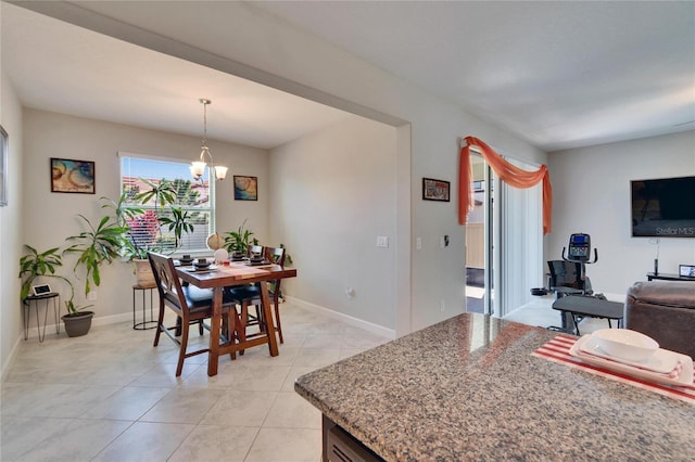 dining space with an inviting chandelier, light tile patterned floors, and baseboards