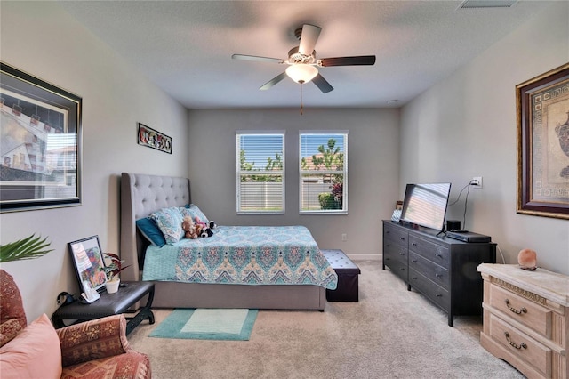 bedroom featuring light colored carpet, a textured ceiling, and a ceiling fan