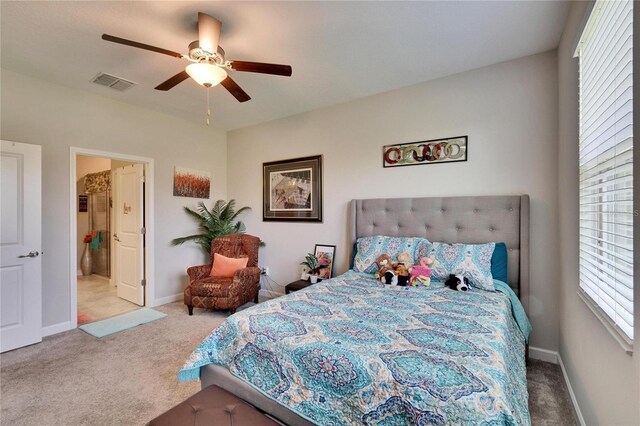 carpeted bedroom featuring connected bathroom, baseboards, visible vents, and ceiling fan