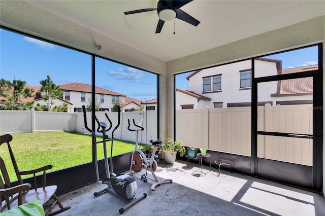 unfurnished sunroom with a residential view and a ceiling fan