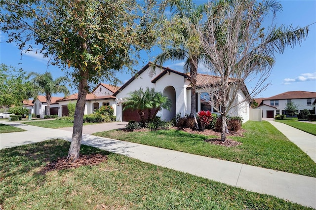 mediterranean / spanish home with stucco siding, a front lawn, a tile roof, concrete driveway, and a garage