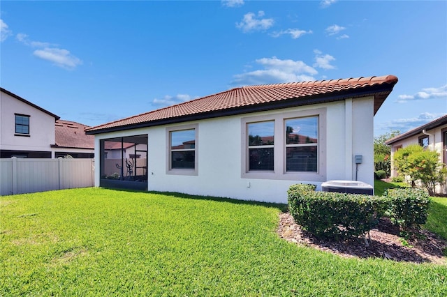 back of property with stucco siding, a tile roof, a yard, and fence