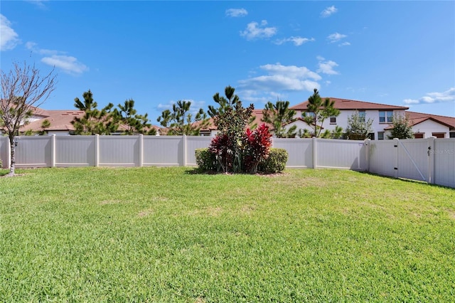 view of yard with a fenced backyard and a gate