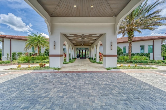 entrance to property with stucco siding, french doors, and ceiling fan