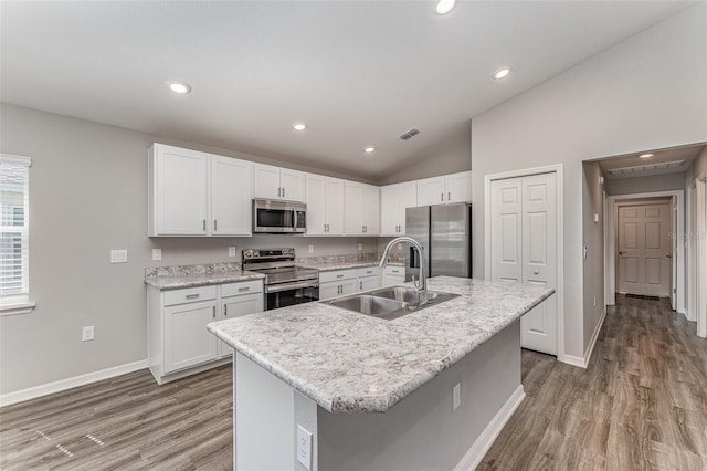 kitchen with light wood finished floors, appliances with stainless steel finishes, vaulted ceiling, white cabinetry, and a sink