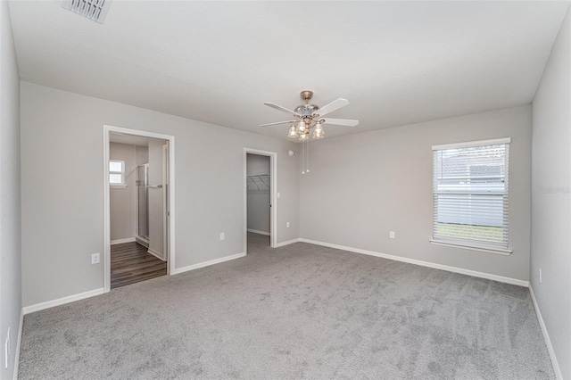 unfurnished bedroom with baseboards, visible vents, ceiling fan, a spacious closet, and carpet flooring