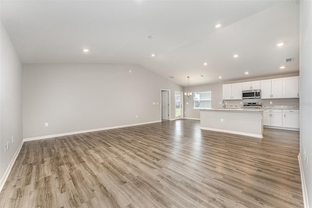 unfurnished living room featuring light wood-type flooring, baseboards, and vaulted ceiling