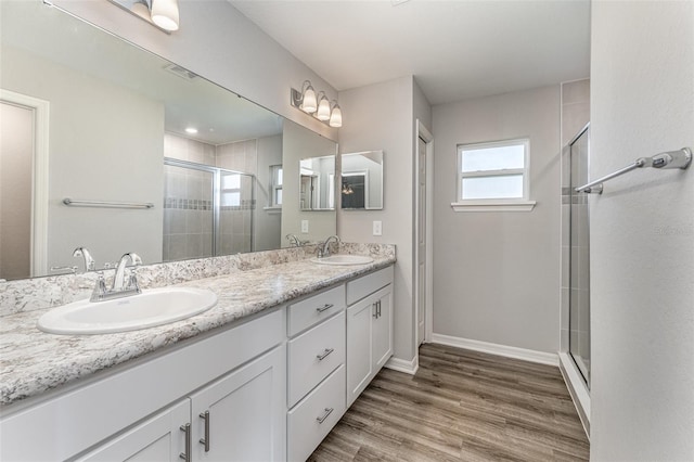 full bathroom with double vanity, wood finished floors, a sink, and a shower stall