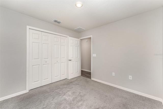 unfurnished bedroom featuring a closet, carpet, visible vents, and baseboards