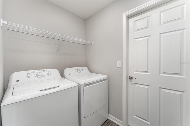 laundry area with laundry area, washing machine and dryer, and baseboards