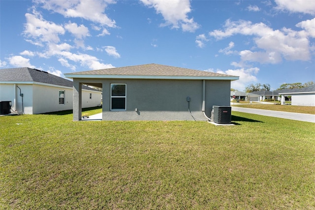 back of house with cooling unit, a yard, and stucco siding