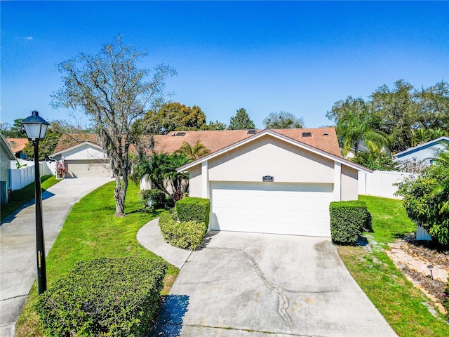 view of front of house with driveway, fence, a front lawn, and stucco siding