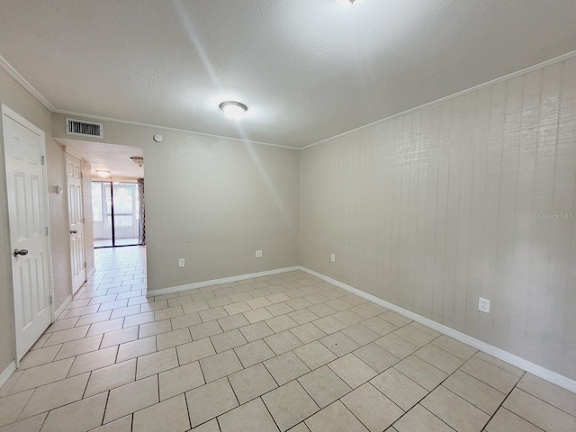 unfurnished room with light tile patterned floors, baseboards, visible vents, a textured ceiling, and crown molding