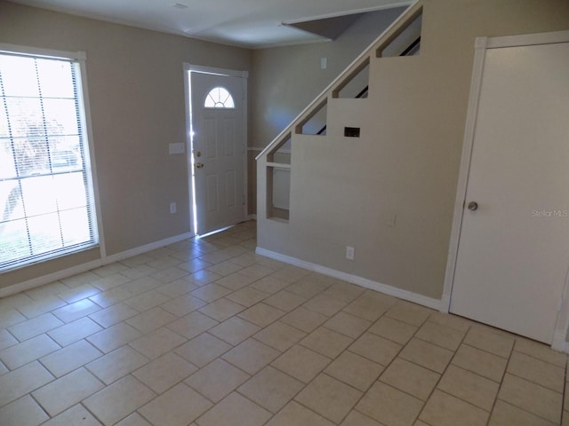 entryway with stairs, baseboards, and light tile patterned floors