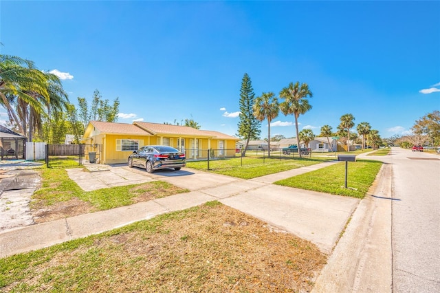 view of front facade featuring concrete driveway, a front yard, and fence