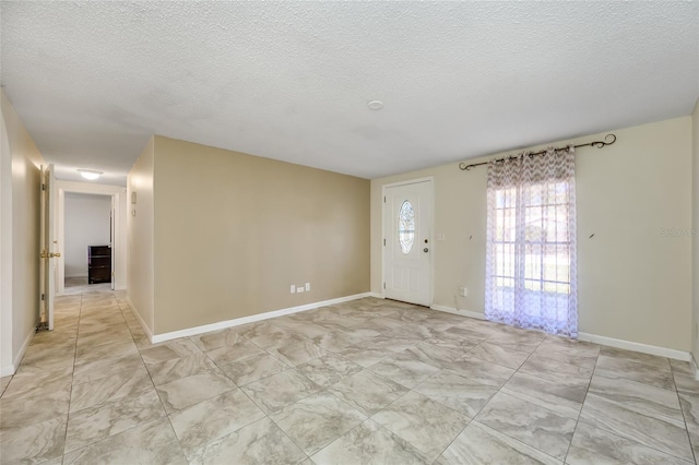 foyer featuring a textured ceiling and baseboards