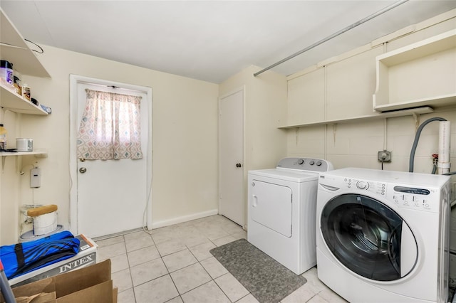 laundry area with laundry area, light tile patterned floors, baseboards, and washing machine and clothes dryer