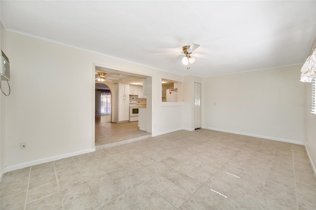 spare room with crown molding, a ceiling fan, and baseboards