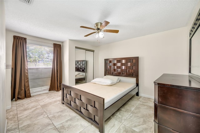 bedroom with a ceiling fan, a closet, a textured ceiling, and baseboards