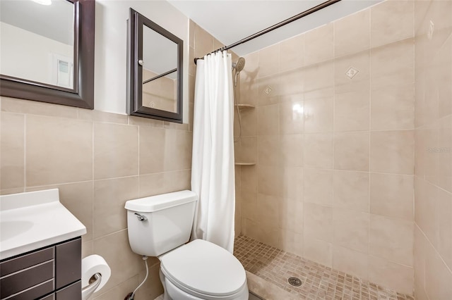 full bath featuring toilet, a tile shower, vanity, and tile walls