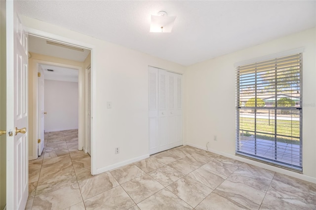 unfurnished room featuring marble finish floor, a textured ceiling, and baseboards