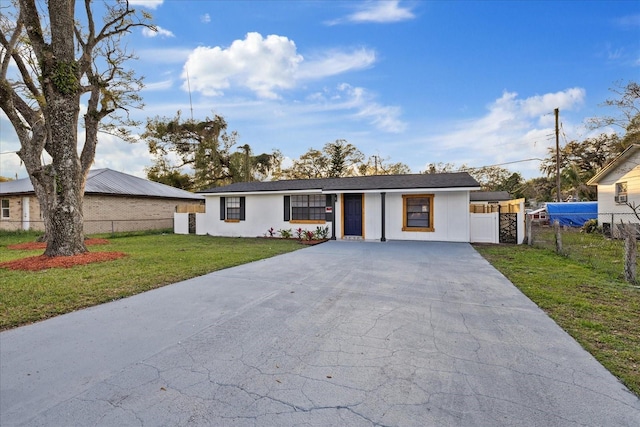 ranch-style house with driveway, a front yard, and fence